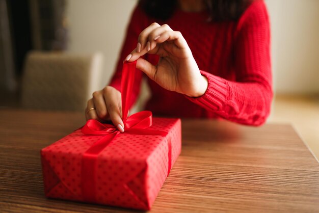 Weibliche Hände öffnen rote Geschenkbox Auspacken eines Geschenks Valentinstag-Feier-Konzept