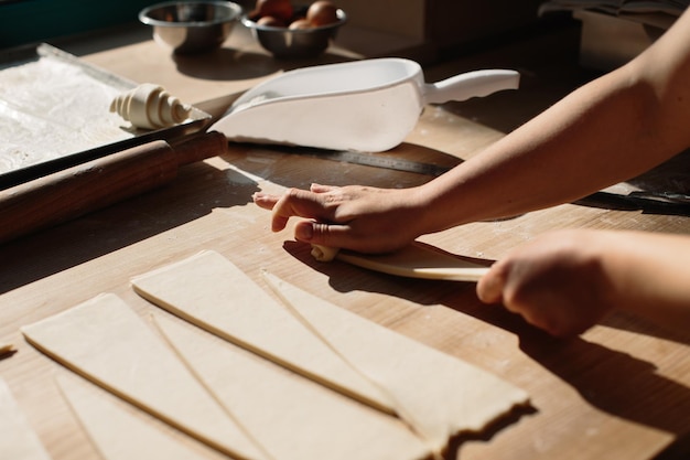 Weibliche Hände rollen Teig zu Brötchen Backprozess Herstellung von Croissants Ausgewähltes Fokuskonzept für die Bäckerei