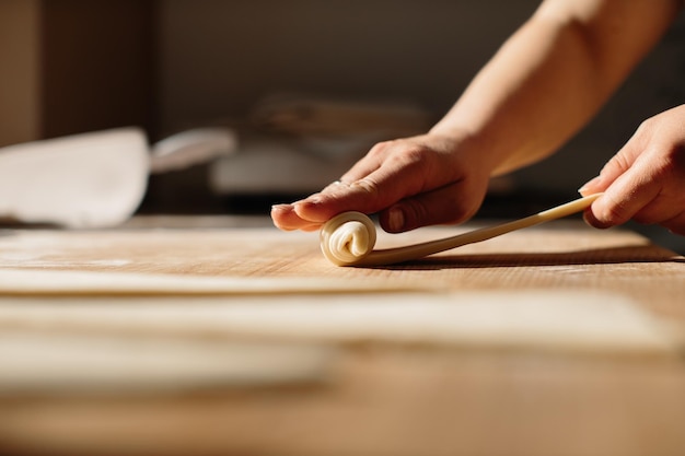 Weibliche Hände rollen Teig zu Brötchen Backprozess Herstellung von Croissants Ausgewähltes Fokuskonzept für die Bäckerei
