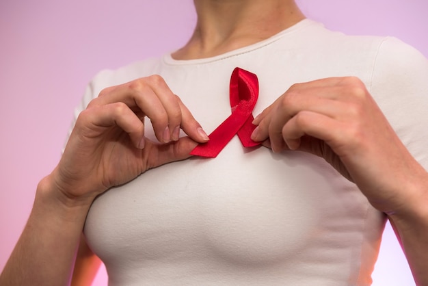 Weibliche Hände schließen oben mit rotem Band. AIDS-Unternehmenskonzept. Soziale Werbung