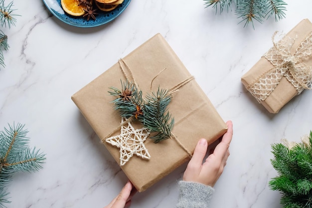 Weibliche Hände schmücken Weihnachtsgeschenk