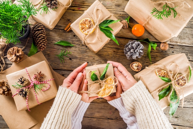 Weibliche Hände schmücken Weihnachtsgeschenkbox.