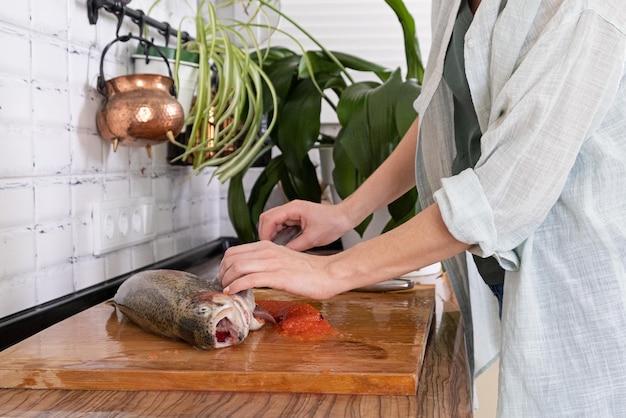 Weibliche Hände schneiden Filet von rotem Fisch Roter Kaviar Entfernen von Fischgräten Schlachten von rotem FischfleischxAxAFood-Konzept