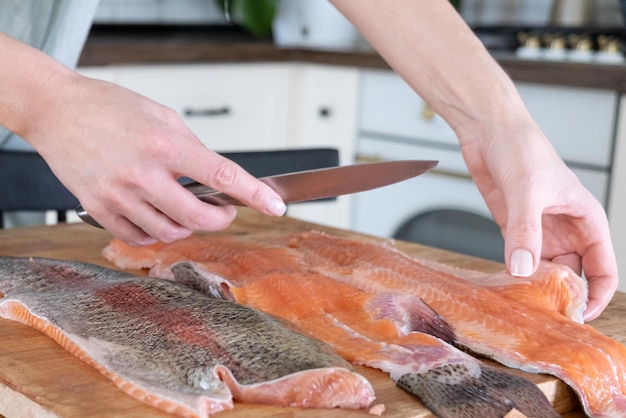 Weibliche Hände schneiden Filet von rotem Fisch Roter Kaviar Entfernen von Fischgräten Schlachten von rotem FischfleischxAxAFood-Konzept