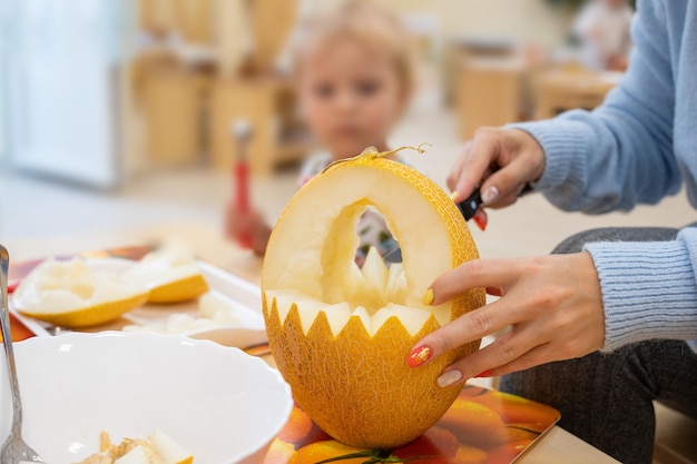 Weibliche Hände schneiden Kürbis zu Halloween