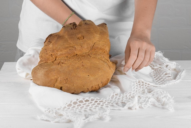 Weibliche Hände setzen das Brot von Matera Pane di Matera auf weißem Hintergrund Typisches süditalienisches Sauerteigbrot