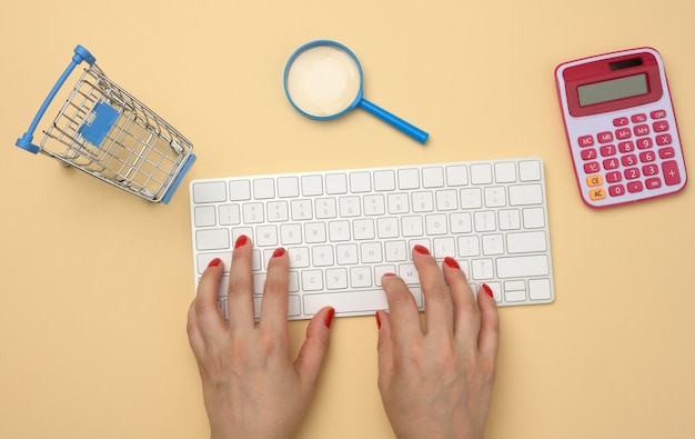 Weibliche Hände und weiße drahtlose Tastatur, Stapel Papierquittungen und Lupe auf gelbem Hintergrund, Budgetanalysekonzept, Einsparungen