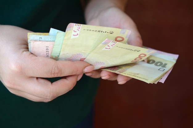 Weibliche Hände zählen große Mengen an ukrainischem Geld während der Gehaltsperiode in der Ukraine reiches Lebenskonzept