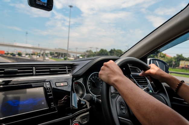 Weibliche Hand am Lenkrad Autofahren auf der Straße.