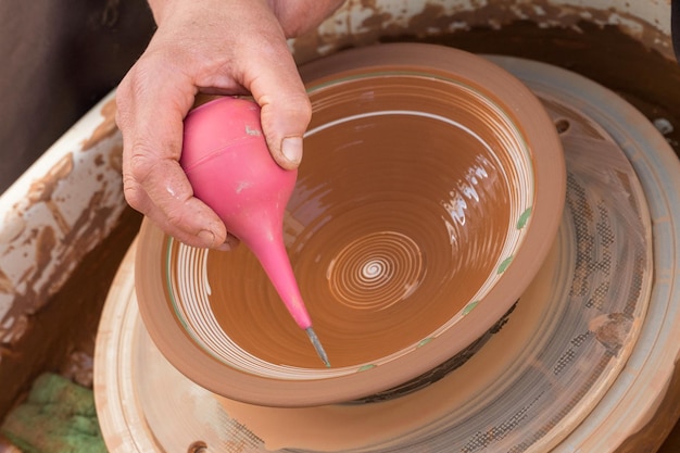 Weibliche Hand bemalt Tonteller auf einer Töpferscheibe