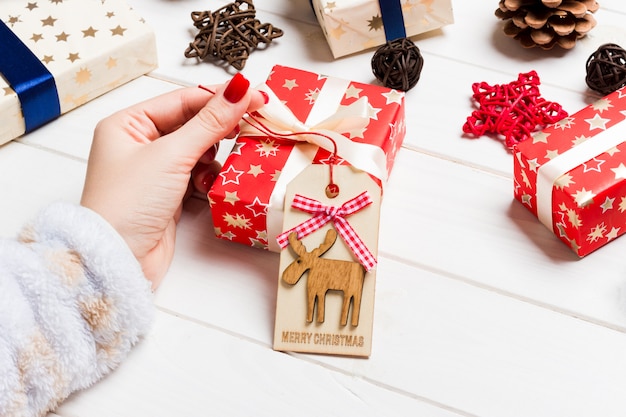 Weibliche Hand der Draufsicht binden Geschenk des neuen Jahres auf festlichem hölzernem. Weihnachtszeit