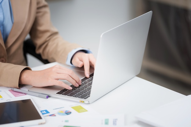 Weibliche Hand der Nahaufnahme, die auf Laptoptastatur im Büro schreibt