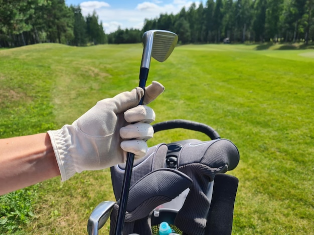 Weibliche Hand des Golfers im Handschuh hält Tasche mit Golfschlägern