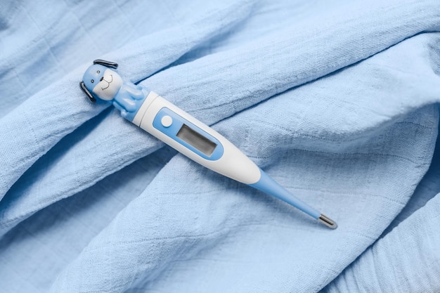 Weibliche Hand, die Babythermometer in Form eines Hundes hält