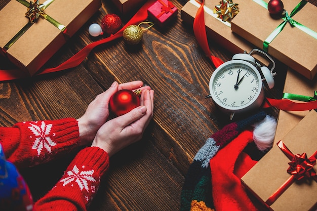 Weibliche Hand, die Bouble nahe Geschenkboxen hält