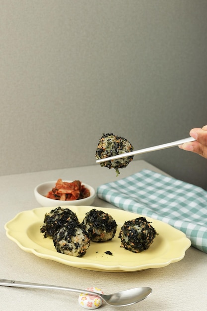 Weibliche Hand, die Chpstick hält, isst Jumeokbap Korean Seaweed Rice Ball