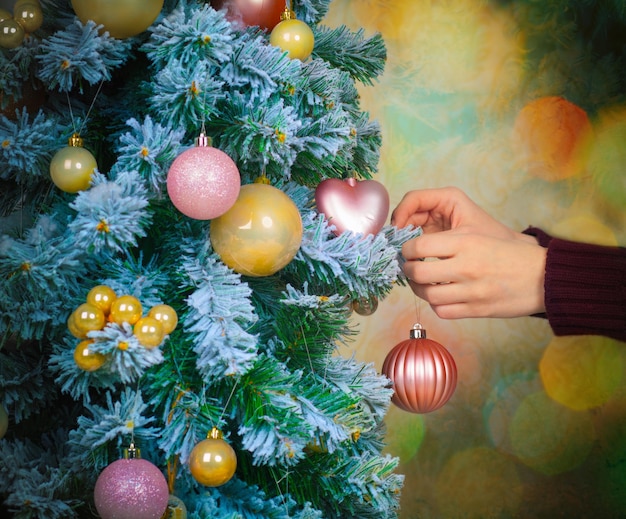 Weibliche Hand, die den Weihnachtsbaum schmückt