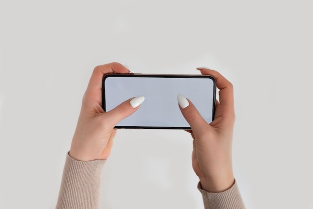 Weibliche Hand, die ein mobiles Smartphone mit weißem Bildschirm hält und berührt, isoliert auf weiß Fotovorlage für beliebige Bilder auf dem Handy-Display Layout mit leicht entfernbarem Hintergrund des Telefonmonitors