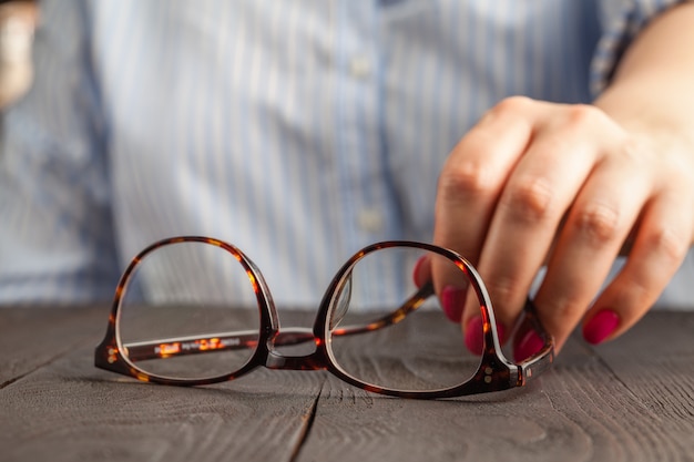 Weibliche Hand, die eine braune gerahmte Brille hält