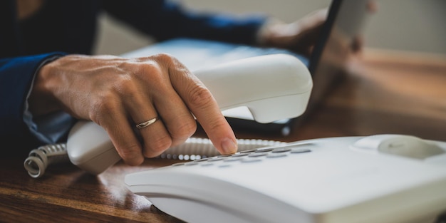 Foto weibliche hand, die einen weißen festnetztelefonhörer hält und eine telefonnummer wählt