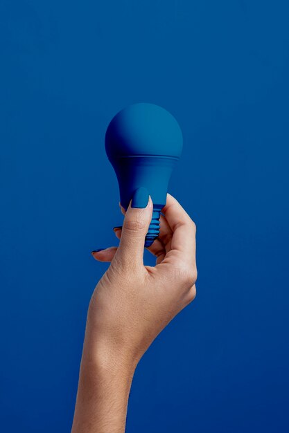 Weibliche Hand, die klassische blaue Glühlampe anhält