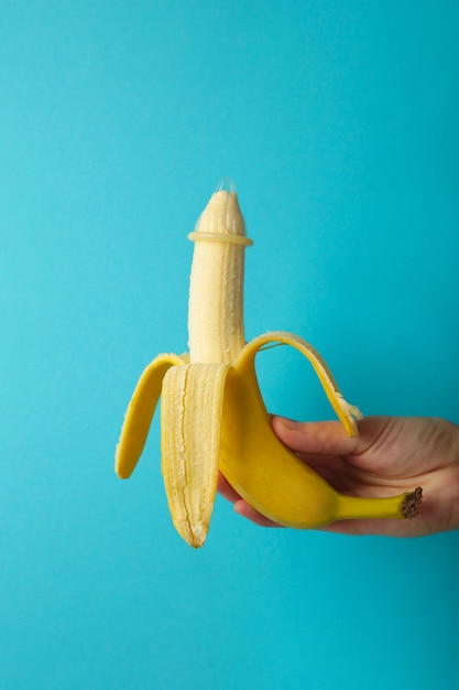 Weibliche Hand, die Kondom auf einer Banane hält Safer-Sex-Konzept