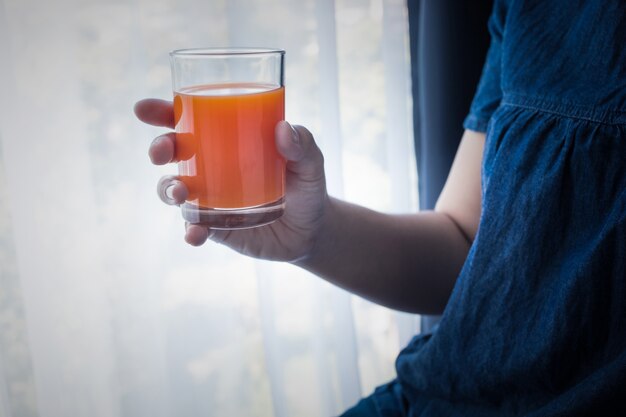 Weibliche Hand, die morgens eine Tasse Orangensaft hält, wenn sie aufwacht.Gesunde Lifestyle-Konzeptideen