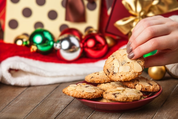 Weibliche Hand, die Plätzchen am Weihnachtsgeschenkhintergrund hält