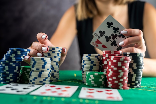 Weibliche Hand, die Pokerchips vom Stapel am runden Pokertisch nimmt