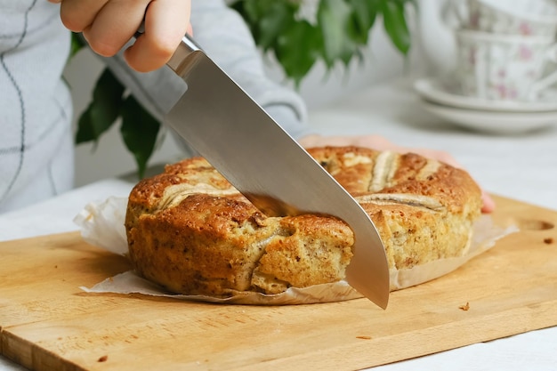 Weibliche Hand, die süßes Bananenbrot schneidet