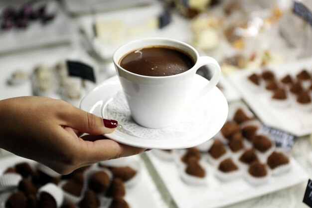 Weibliche Hand, die Tasse Kaffee auf Tischhintergrund hält