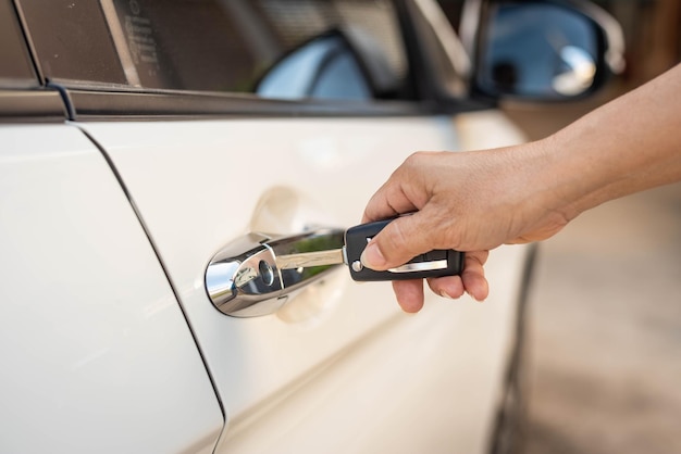 Weibliche Hand drückt Fernbedienungsschlüssel eines weißen Autos