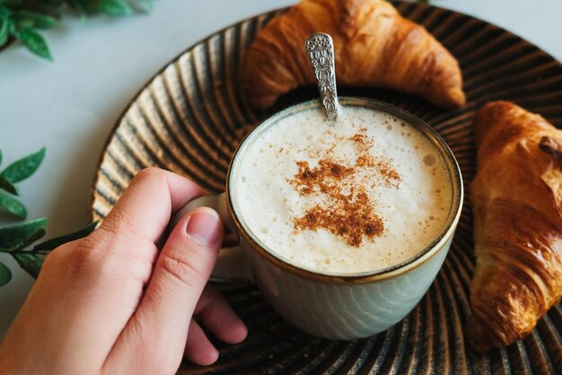 Weibliche Hand hält Cappuccino-Kaffeetasse