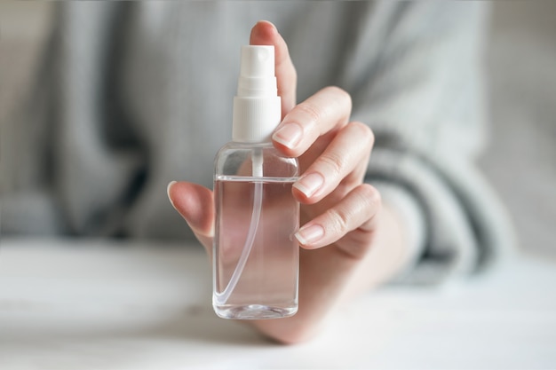 Weibliche Hand hält eine Flasche eines antibakteriellen Gels, Alkoholspray von Coronavirus-Bakterien