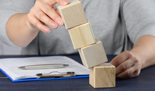 Weibliche Hand hält fallende Würfel auf dem Tisch. Das Konzept einer Managerkrise, die das Unternehmen über Wasser hält, das Unternehmen stabilisiert. Entwicklung der Entwicklungsstrategie