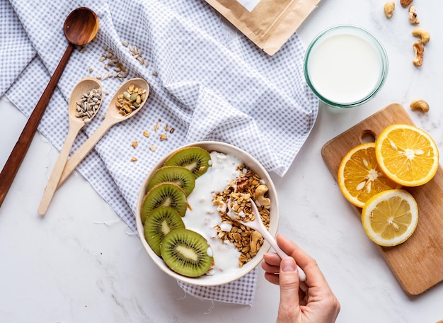 Weibliche Hand hält Löffel über gesunde Frühstücksschüssel und genießt Detox-Mahlzeit auf dem Tisch