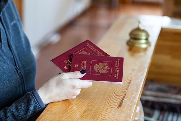 Weibliche Hand hält russischen Pass am hölzernen Empfangsschalter