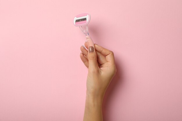 Weibliche Hand halten Rasiermesser auf rosa