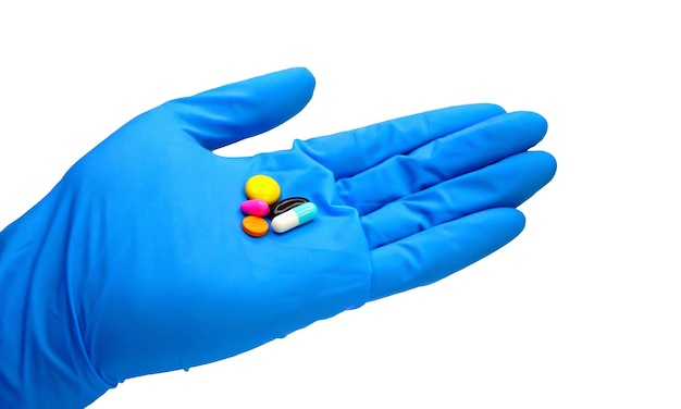 weibliche Hand im blauen medizinischen Handschuh, die weiße runde Pille auf weißem Hintergrund ausdehnt