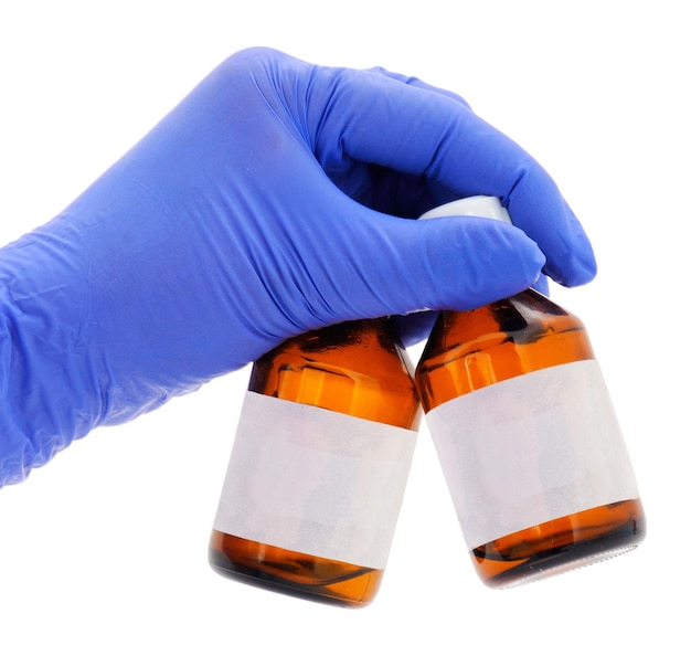Weibliche Hand im medizinischen Handschuh des blauen Latex hält eine braune Glasflasche für Medikamente