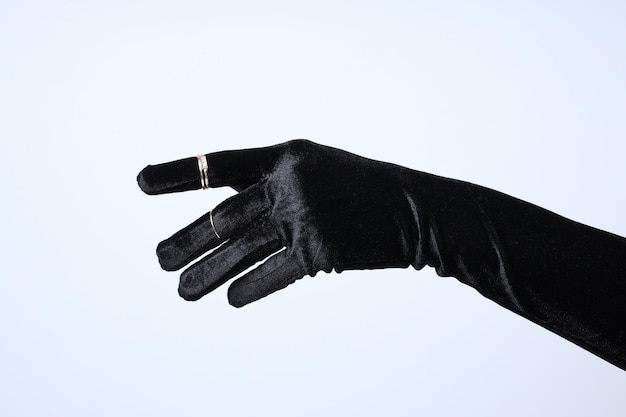 Weibliche Hand im schwarzen Handschuh mit Ringen auf weißem Hintergrund