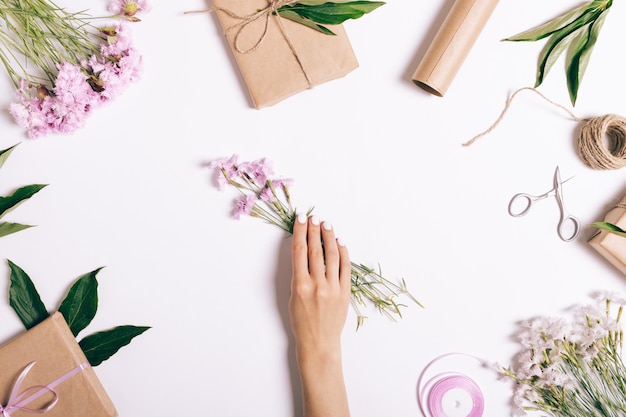 Weibliche Hand legt einen Strauß rosa Blumen auf den Tisch