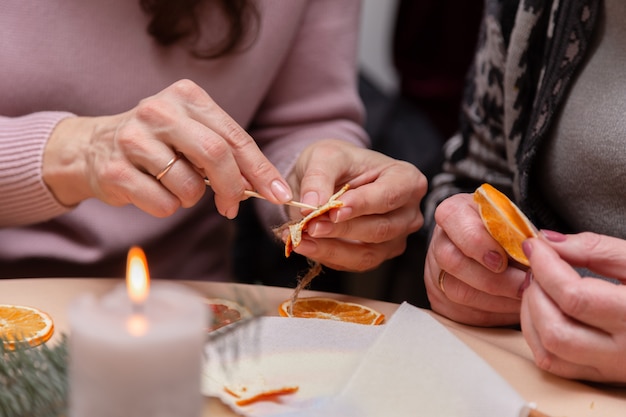 weibliche Hand machen Dekorationen aus getrockneten Orangen, Sterne aus Mandarine und Zimt