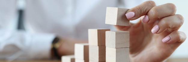 Foto weibliche hand macht holzwürfel im turm