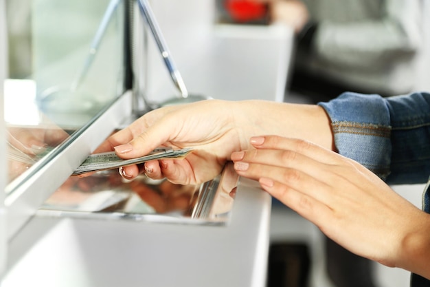 Weibliche Hand mit Geld im Kassefenster Währungsumtauschkonzept