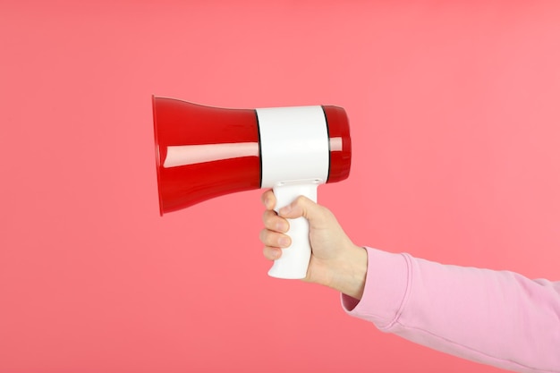 Weibliche Hand mit Megaphon auf rosa Hintergrund