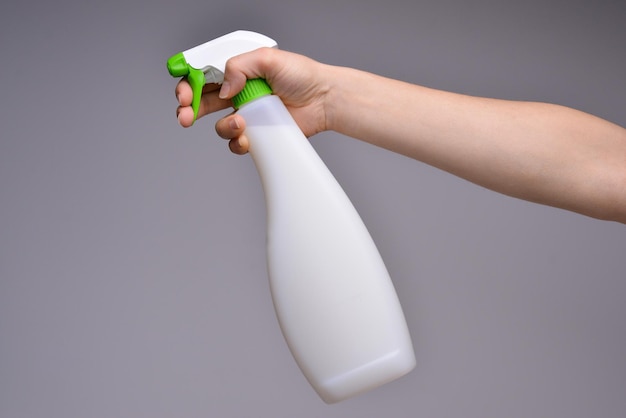 Weibliche Hand mit Sprühgerät isoliert Die Hand des Reinigers, die eine weiße chemische Sprühflasche hält