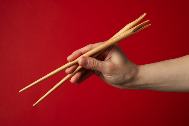 Weibliche Hand mit Stäbchen auf roter Oberfläche