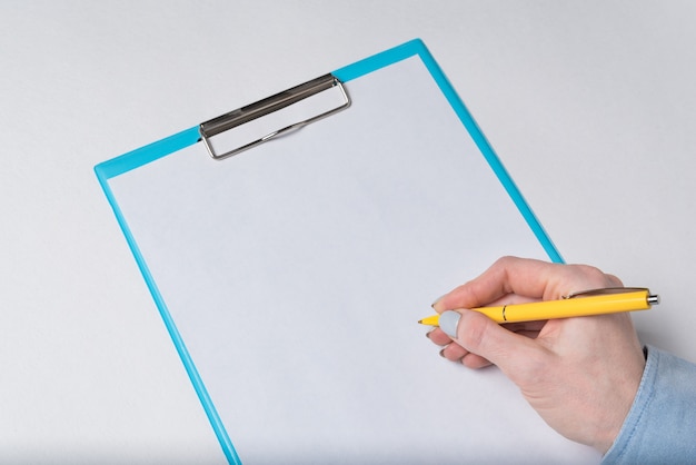 Weibliche Hand mit Stift auf einem leeren Blatt Papier