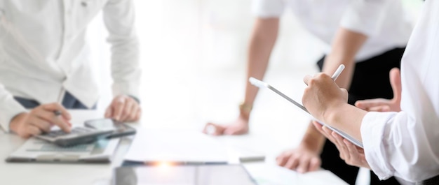 Weibliche Hand mit Stift und Tablet, die mit Teamdesignern im modernen Büro arbeiten